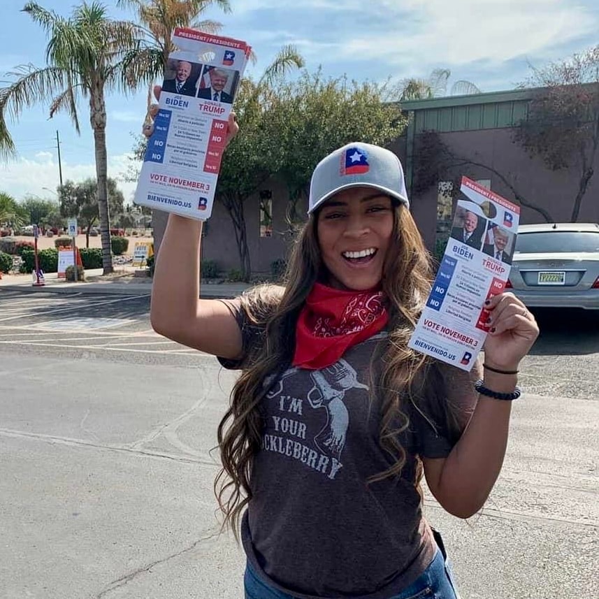 Woman holding Bienvenido voter guides outdoors